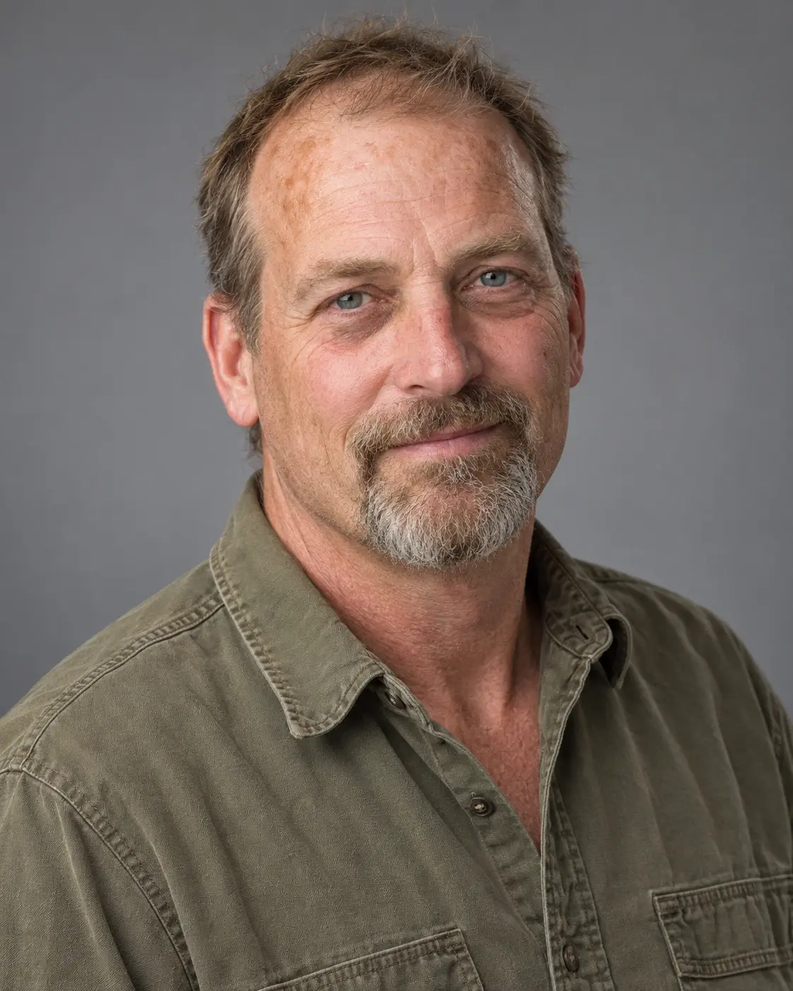 Mark Moody in an olive work shirt against a plain gray studio background.